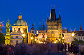 Old Town Bridge Tower and the dome of St. Francis of Assisi Church at Charles Bridge at twilight, UNESCO World Heritage Site, Prague, Czechia, Europe