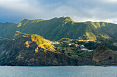 Häuser auf einer Klippe in den Bergen bei Sonnenuntergang, in der Nähe von Porto da Cruz, Distrikt Machico, Madeira, Portugal, Atlantik, Europa