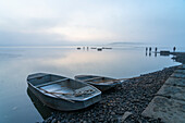 Rowing boats on shore  with fishermen in background preparing for fish harvest on foggy morning, Rozmberk Pond, UNESCO Biosphere, Trebon, Jindrichuv Hradec District, South Bohemian Region, Czech Republic (Czechia), Europe