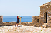 Frau schaut durch ein Teleskop auf dem Dach der Ali Pasha Tepelena Festung in Porto Palermo, Ionische Küste, Albanien, Europa