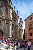 Ein schöner Blick auf die historische Kathedrale in Granada, Spanien, mit Touristen, die sich an einem sonnigen Tag versammelt haben. Die atemberaubende Architektur und die lebhafte Atmosphäre sind gut zu erkennen.