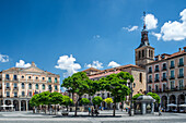 Blick auf das Juan-Bravo-Theater und die San-Miguel-Kirche auf der Plaza Mayor in Segovia, Kastilien und Leon, Spanien. Schöne architektonische Wahrzeichen unter einem klaren blauen Himmel.