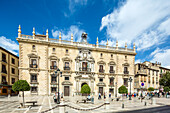 Beautiful view of Edificio de la Audiencia located in Plaza Nueva, Granada, España under a clear blue sky with visitors.