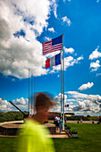 Eine Gedenkstätte am Utah Beach in der Normandie, Frankreich, mit amerikanischen und französischen Flaggen und Besuchern, die den historischen Ort erkunden.