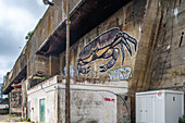 Exterior of the German World War II submarine base in Lorient, Brittany, France, featuring street art and graffiti on concrete structures.