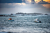 Scenic view of boats anchored in the rough sea along the Quiberon Peninsula in Brittany, France during a cloudy day.