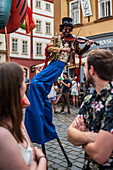 Künstlerin spielt Geige, während sie auf Stelzen bei der Puppenparade vom Marienplatz zum Altstädter Ring läuft, während des Prager Straßentheaterfestivals Behind the Door, Prag, Tschechische Republik