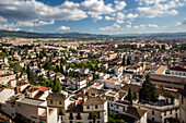 Tilt-shift photograph capturing the scenic cityscape of Granada, Andalusia, Spain, as seen from the Alhambra hill.