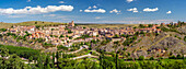 Breiter Panoramablick auf Sepulveda, eine historische Stadt in der Provinz Segovia, Spanien, umgeben von üppigem Grün und dramatischen Hügeln.