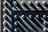 Close up of decorative studs on an iron door of a historic church in Seville, Spain. Shadows create an interesting pattern.