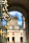 Nahaufnahme eines verzierten Türgriffs im Kloster San Lorenzo de El Escorial, mit Schwerpunkt auf den komplizierten Metallarbeiten.