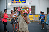 Menschen feiern das Fest Gigantes y Cabezudos in Fuenteheridos, Huelva, Andalusien, Spanien. Traditionelles kulturelles Ereignis mit kostümierten Figuren und Menschenmengen, die die Festlichkeiten genießen.