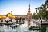 Serene evening view of people boating at Plaza de Espana, Seville, Spain, captured with a tilt-shift effect.