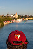 Ein Fan des FC Sevilla mit einer Mütze wartet am Flussufer auf die Ankunft der Mannschaft, um den UEFA-Pokalsieg 2007 zu feiern.