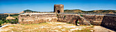 Panoramic view of a beautifully remodeled Moorish castle from the 14th century located in Alanis de la Sierra, Sevilla, Spain with scenic mountain backdrop.