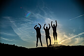 Eine Gruppe von Freunden feiert und springt bei Sonnenuntergang in Villaviciosa de Cordoba, Andalusien, Spanien. Silhouette vor einem schönen Himmel.