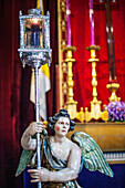 Close up of an angel statue at Hermandad del Silencio in Sevilla, Spain. Vibrant religious decorations in the background.