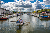 Participants row a boat during a boating event in the picturesque harbor of Vannes, located in Brittany, France.