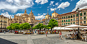 Panoramic view of Plaza Mayor and the Cathedral in Segovia, Spain. A bustling square with people, restaurants, and historic architecture.