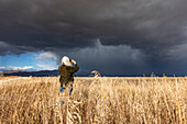 Rear view of woman taking photo of approaching storm with smart phone