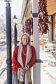 Portrait of smiling woman leaning against column at sidewalk cafe