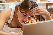 Teenage girl painting in front of laptop