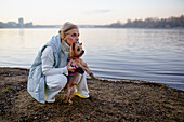 Woman with Yorkshire Terrier on lakeshore