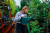 Woman watering plants in greenhouse