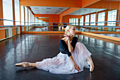 Porträt einer auf dem Boden sitzenden Ballerina im Ballettstudio