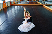 Ballerina sitzend auf dem Boden im Ballettstudio