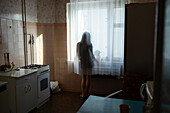 Rear view of woman looking through window in kitchen