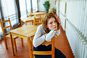 Portrait of pensive woman leaning on wooden chair