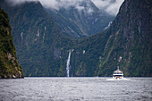 Fähre auf einem Fjord umgeben von Bergen im Fiordland-Nationalpark