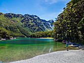 Rear view of woman sitting on lakeshore in Fiordland National Park