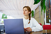 Frau mit Kopfhörern und Laptop am Cafétisch