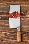 Raw beef steak with thyme on a meat cleaver
