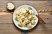 Hausgemachte Pelmeni mit saurer Sahne und Petersilie