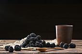 Blueberries with a rustic clay cup on a wooden table