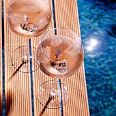 Glasses of rosé wine on a jetty by the pool