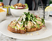 Toasted bread with avocado, grilled chicken and rocket salad