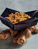 Ground ginger in a bowl on ginger root