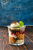 Dessert in a glass with ice, chocolate biscuit and strawberry jam