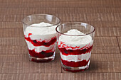 Red and white strawberry layered dessert with yoghurt in a glass