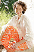 Brunette woman in cream-coloured blouse and orange-patterned trousers