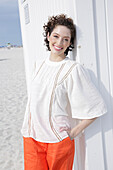 Brunette woman in cream-coloured blouse and orange shorts