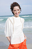 Brunette woman in cream-coloured blouse and orange shorts