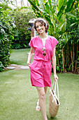 Young woman in pink short jumpsuit with basket bag