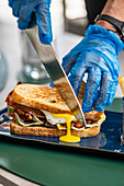 Man cuts sandwich with fried egg and crispy bacon