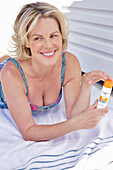 Woman in swimwear holding sun cream on towel