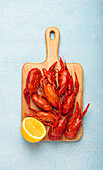 Boiled crayfish with lemon half on a wooden board